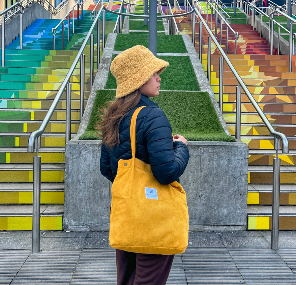 Person wearing a yellow hat and bag standing in front of colorful steps