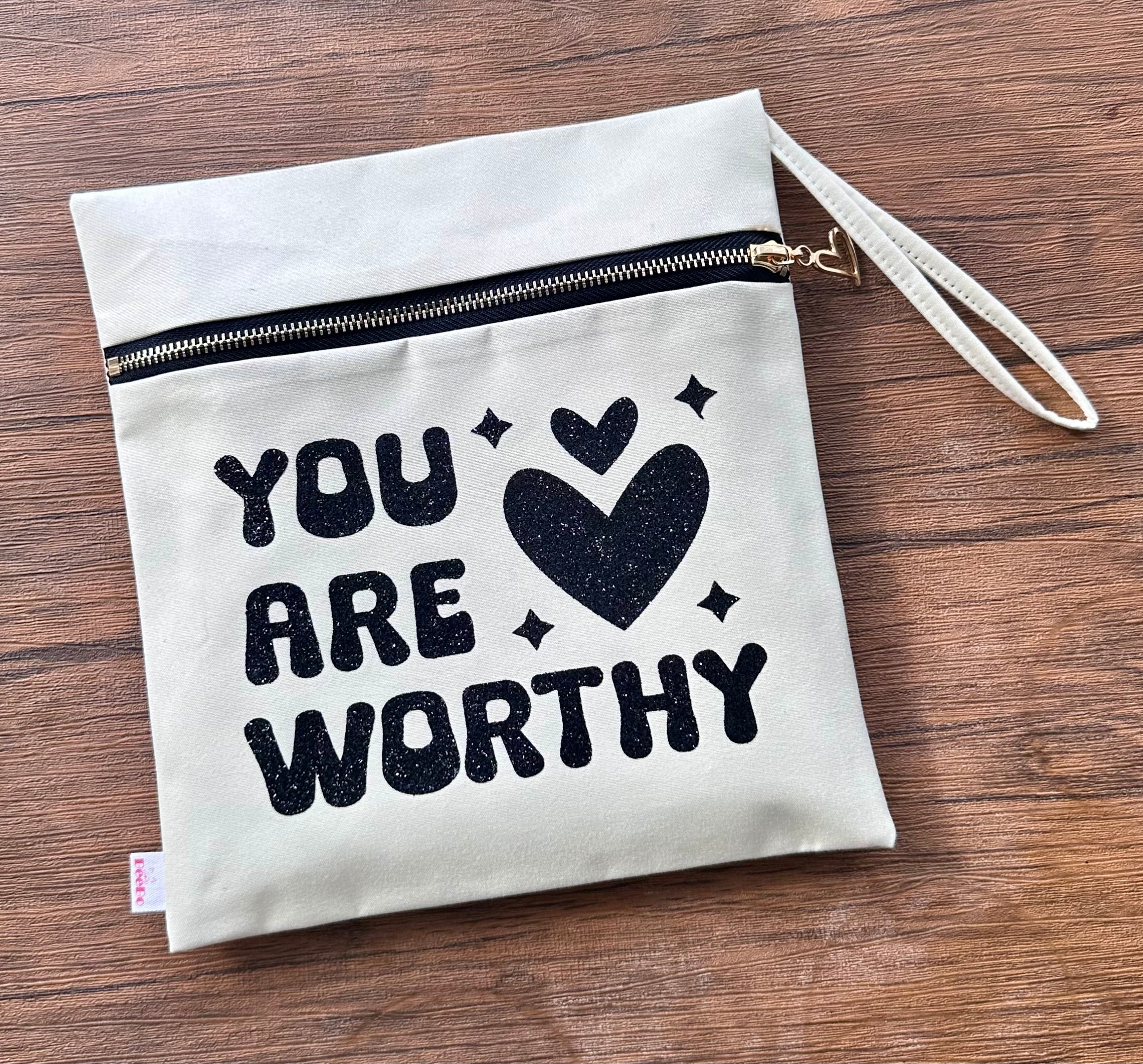 Canvas pouch with 'You are Worthy' text and heart symbol on a wooden surface