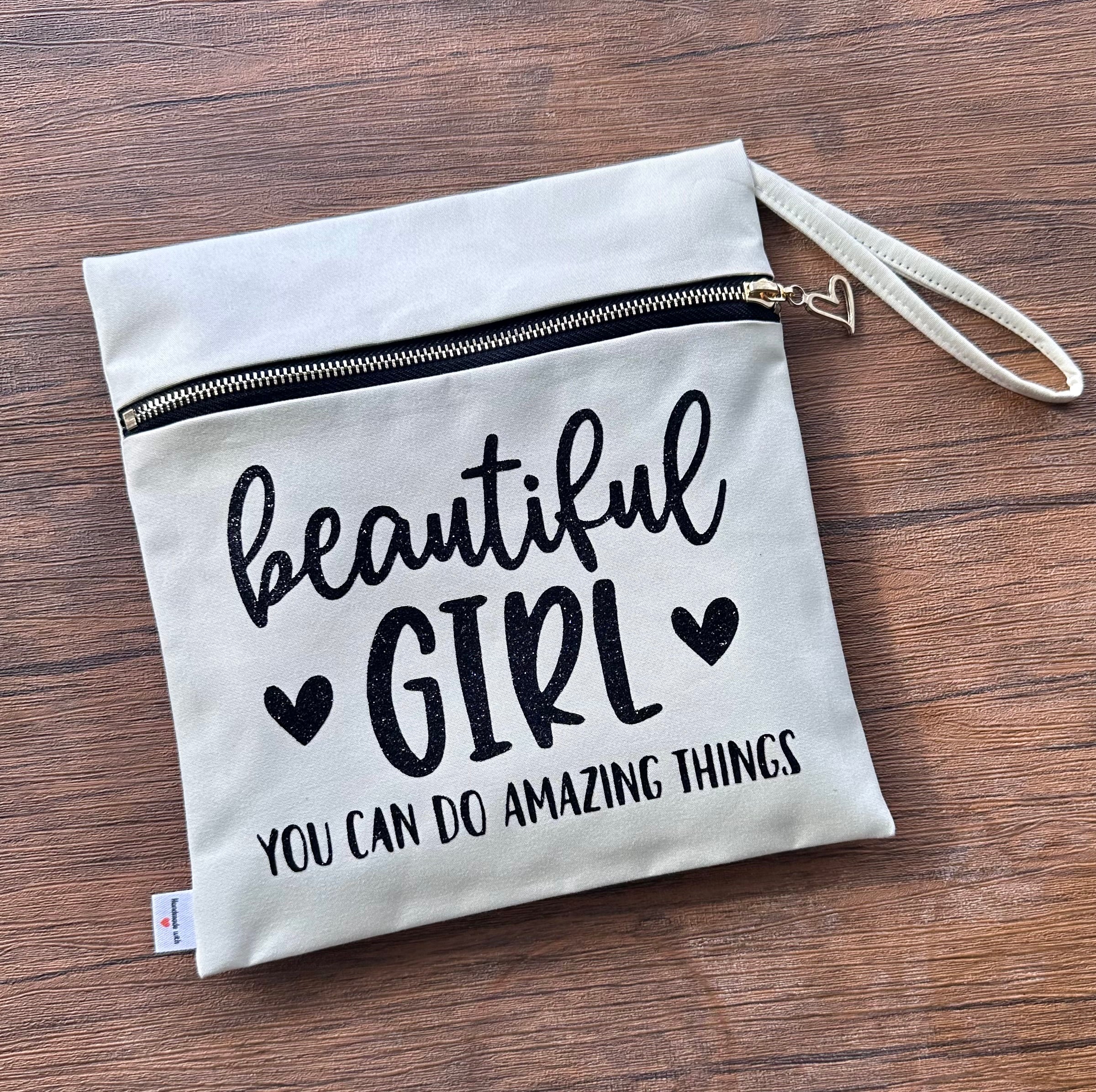 Motivational pouch with 'beautiful girl you can do amazing things' text on a wooden surface
