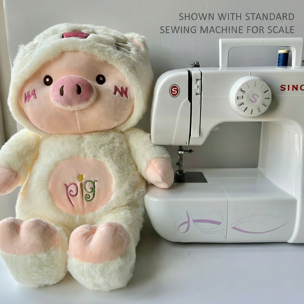 Plush pig toy next to a sewing machine on a white background