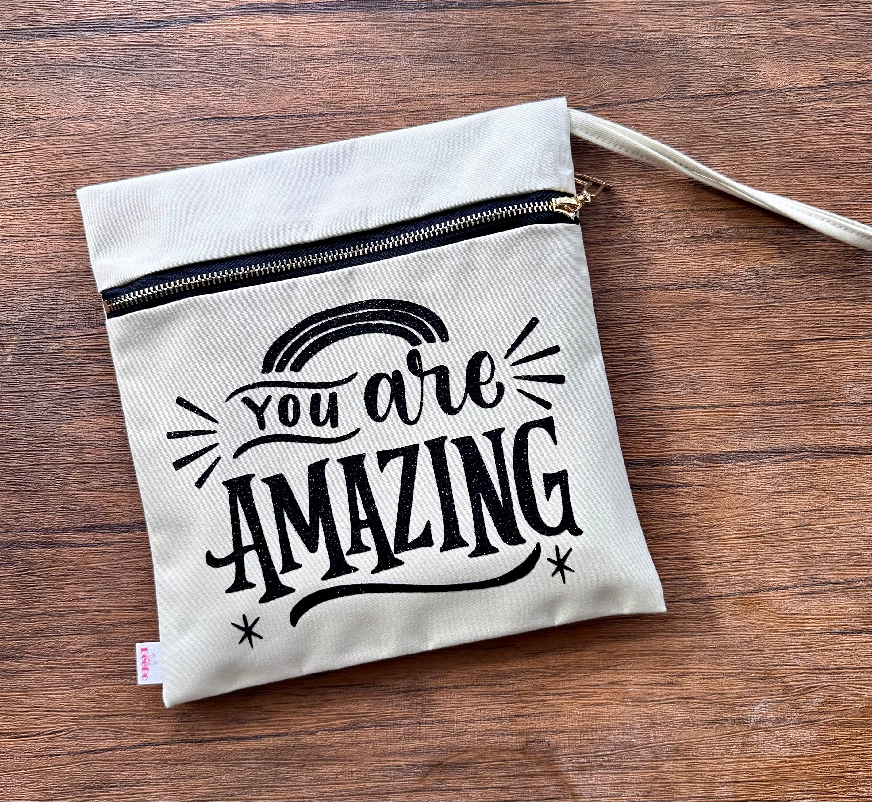 Beige pouch with 'You are Amazing' text on a wooden surface