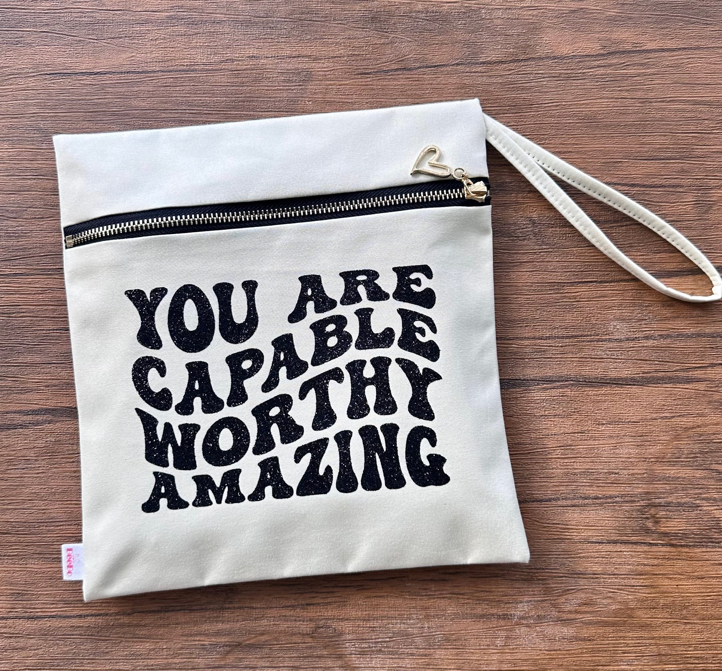 White pouch with motivational text on a wooden surface