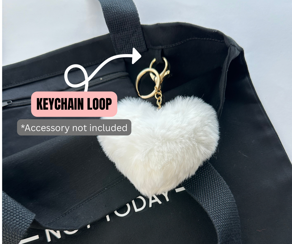 White heart-shaped keychain on a black bag with text indicating a keychain loop accessory not included.