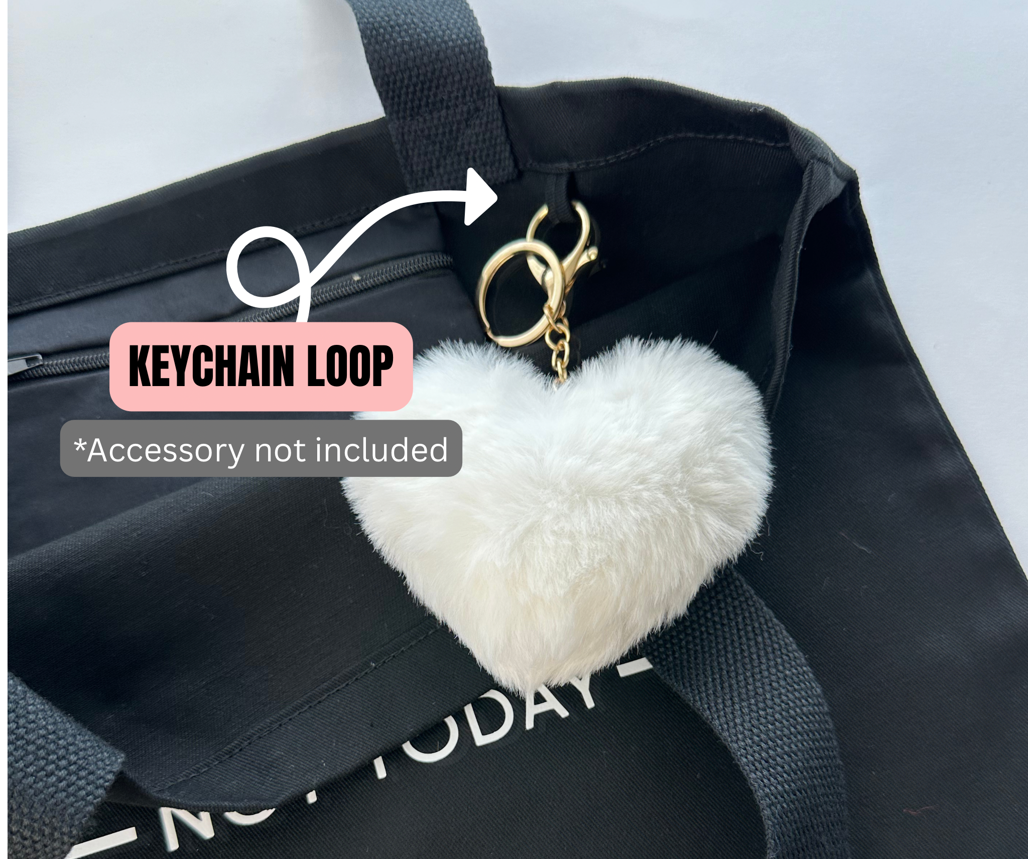 White heart-shaped keychain on a black bag with text indicating a keychain loop accessory not included.