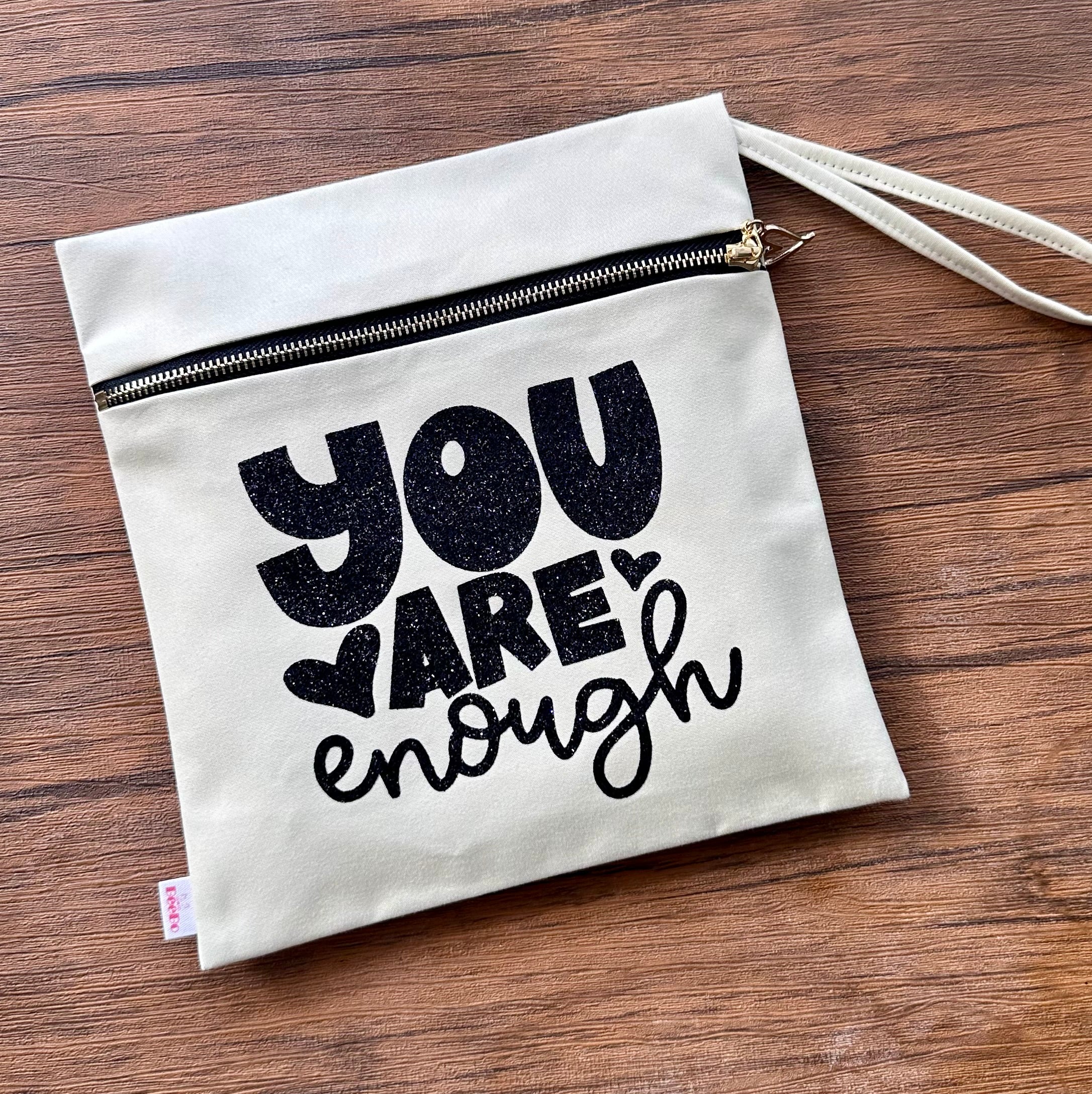 Canvas pouch with 'You are enough' text on a wooden surface