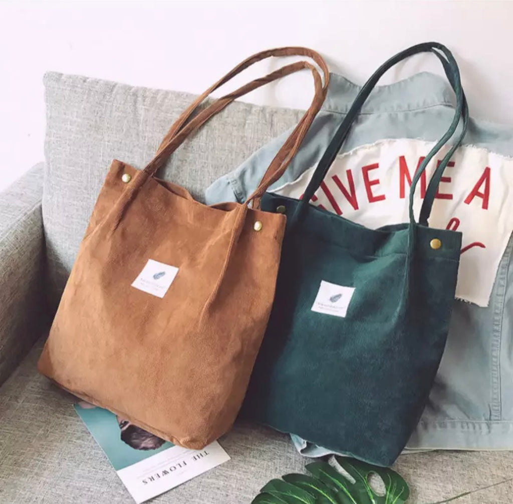 Two tote bags, one brown and one green, on a gray surface with a white background.