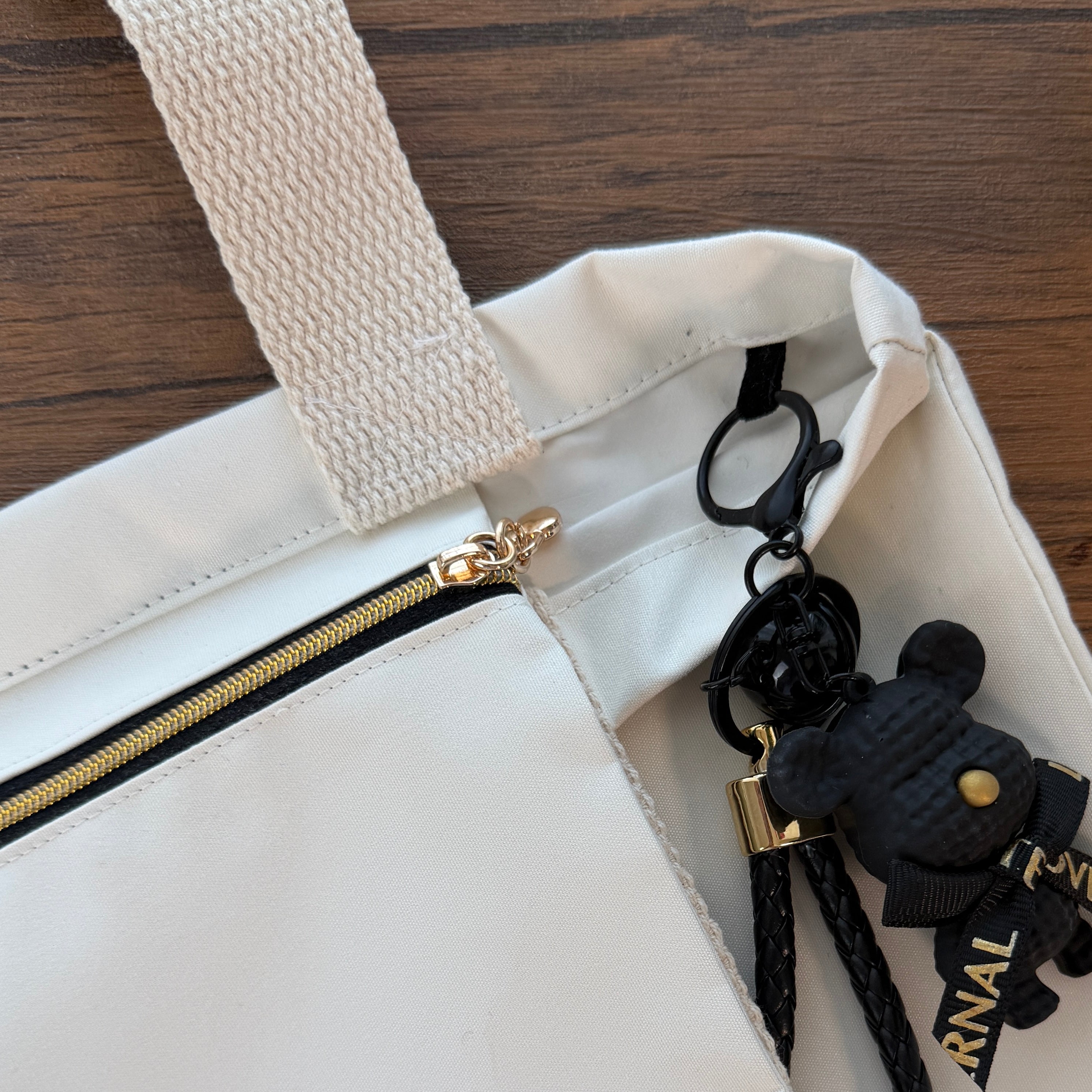 White bag with a gold cute zipper and black keychain on a wooden surface, handmade tote bag, gifts for her UK