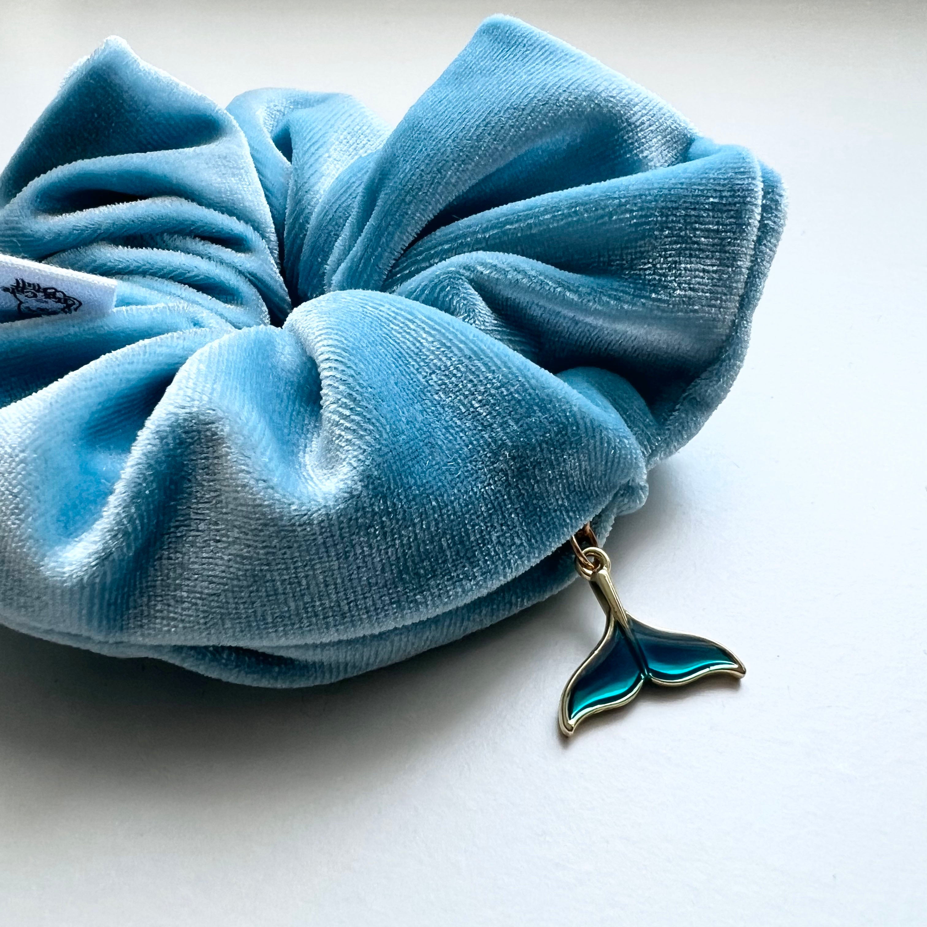Blue scrunchie with a whale tail charm on a white background