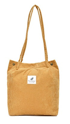 Brown tote bag with a small white label on a white background