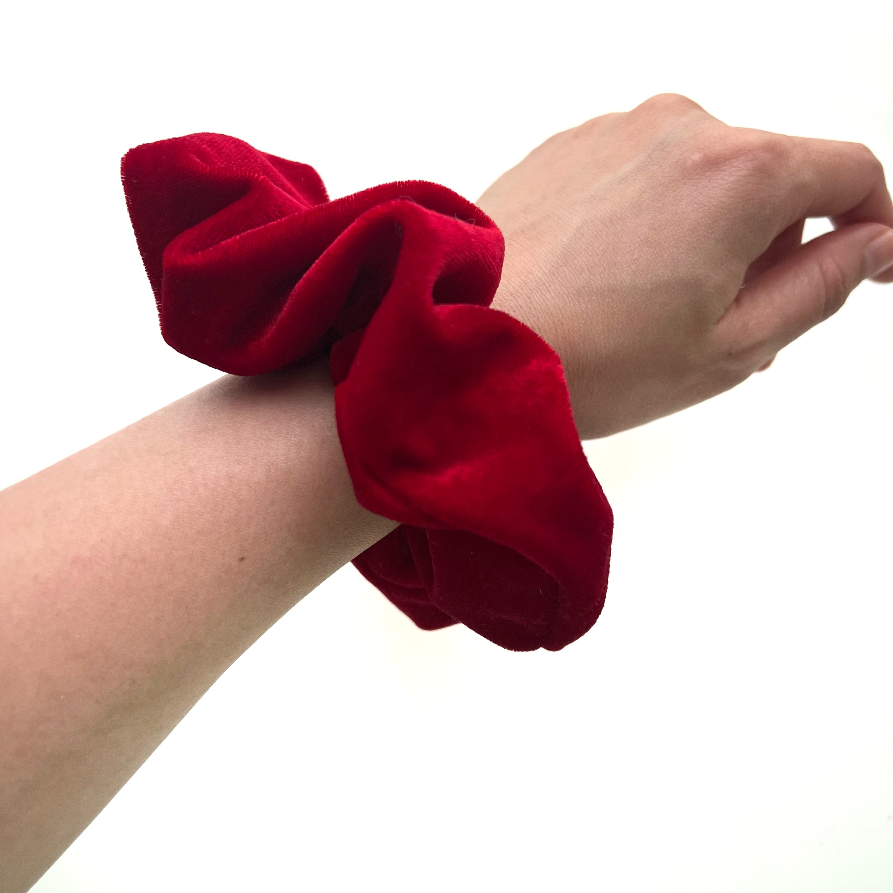 Red scrunchie on a wrist against a white background