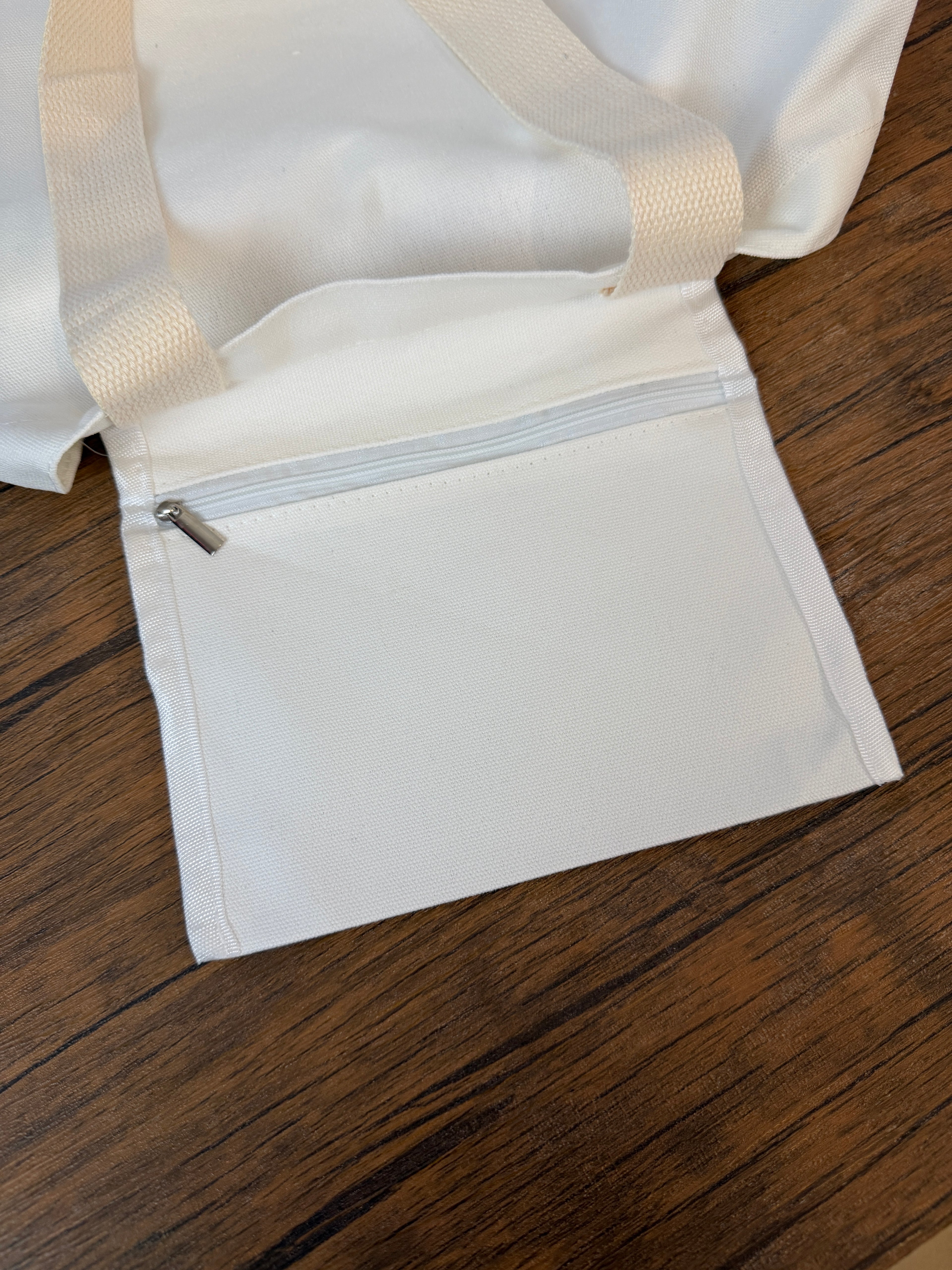White garment bag with a zipper on a wooden surface