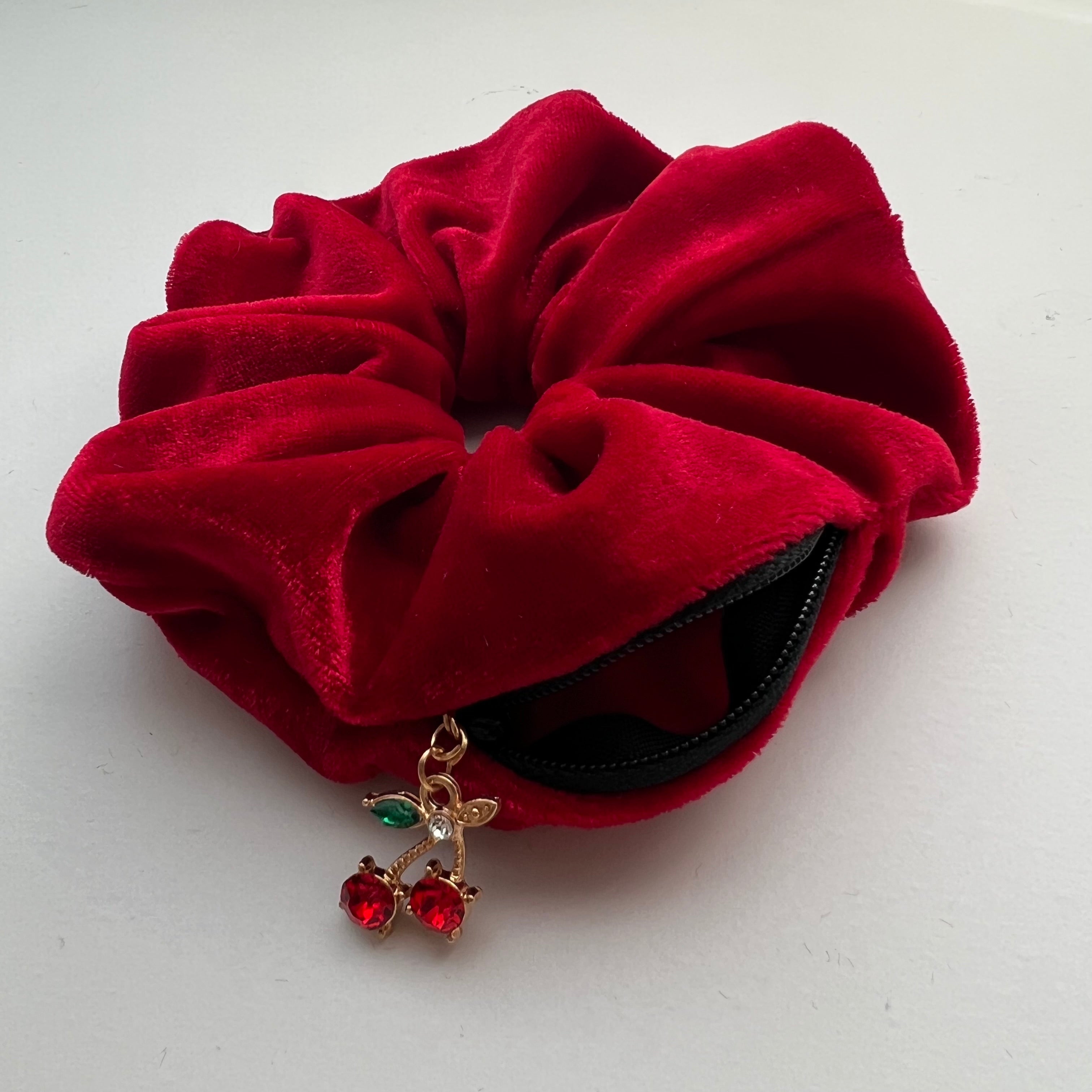 Red scrunchie with zip pocket and a cherry charm on a white background