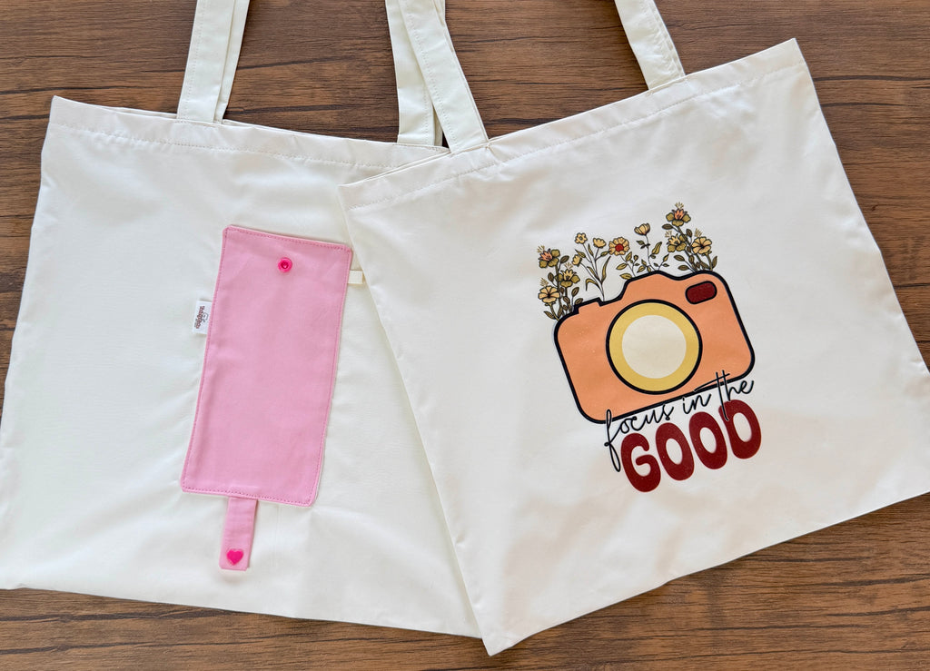 White tote bag with pink ice cream cone pouch and camera graphic on wooden surface
