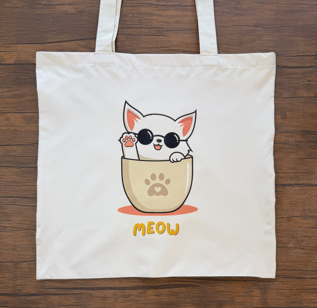 Tote bag with a cat illustration and 'MEOW' text on a wooden surface