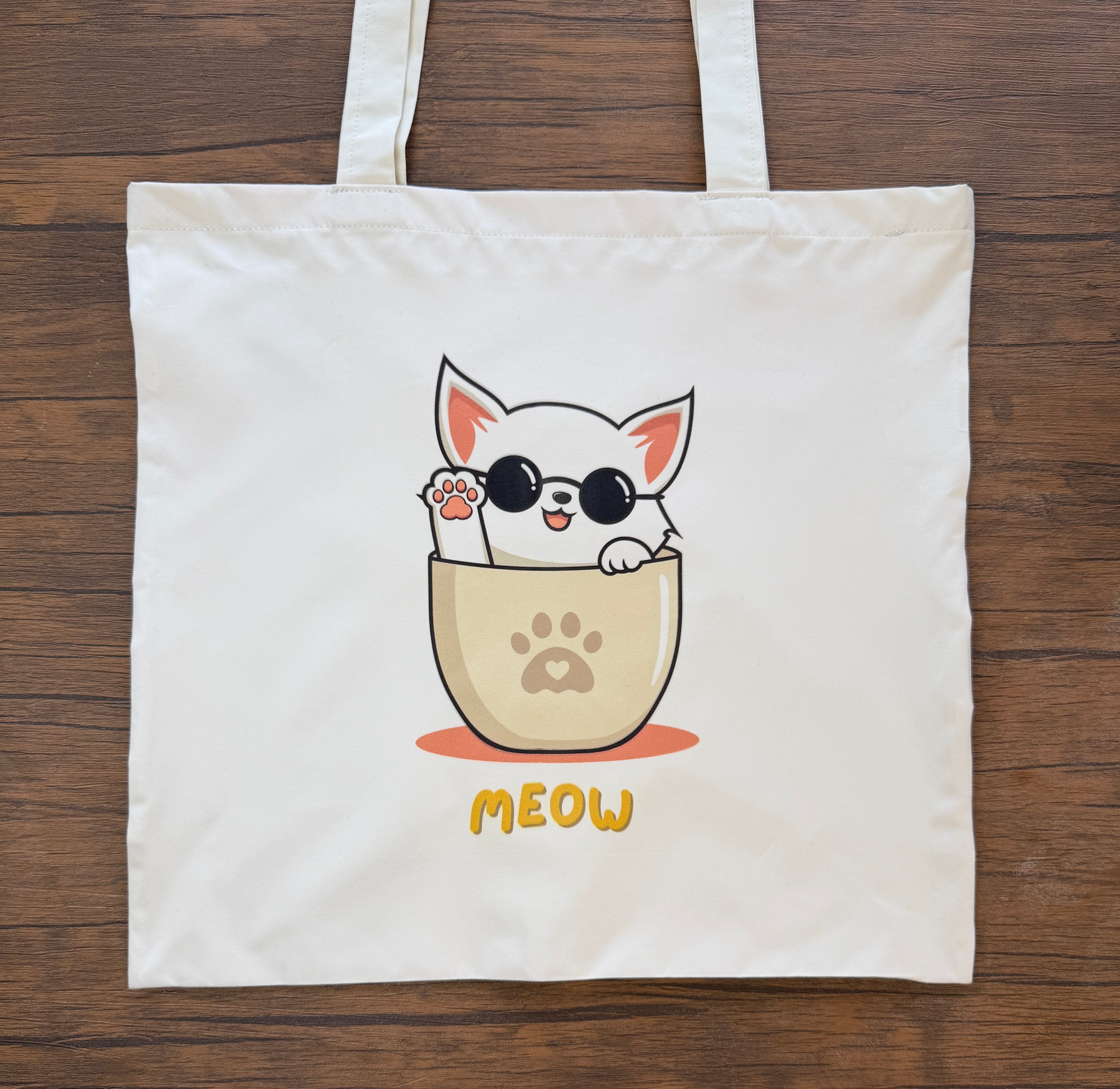 Tote bag with a cat illustration and 'MEOW' text on a wooden surface