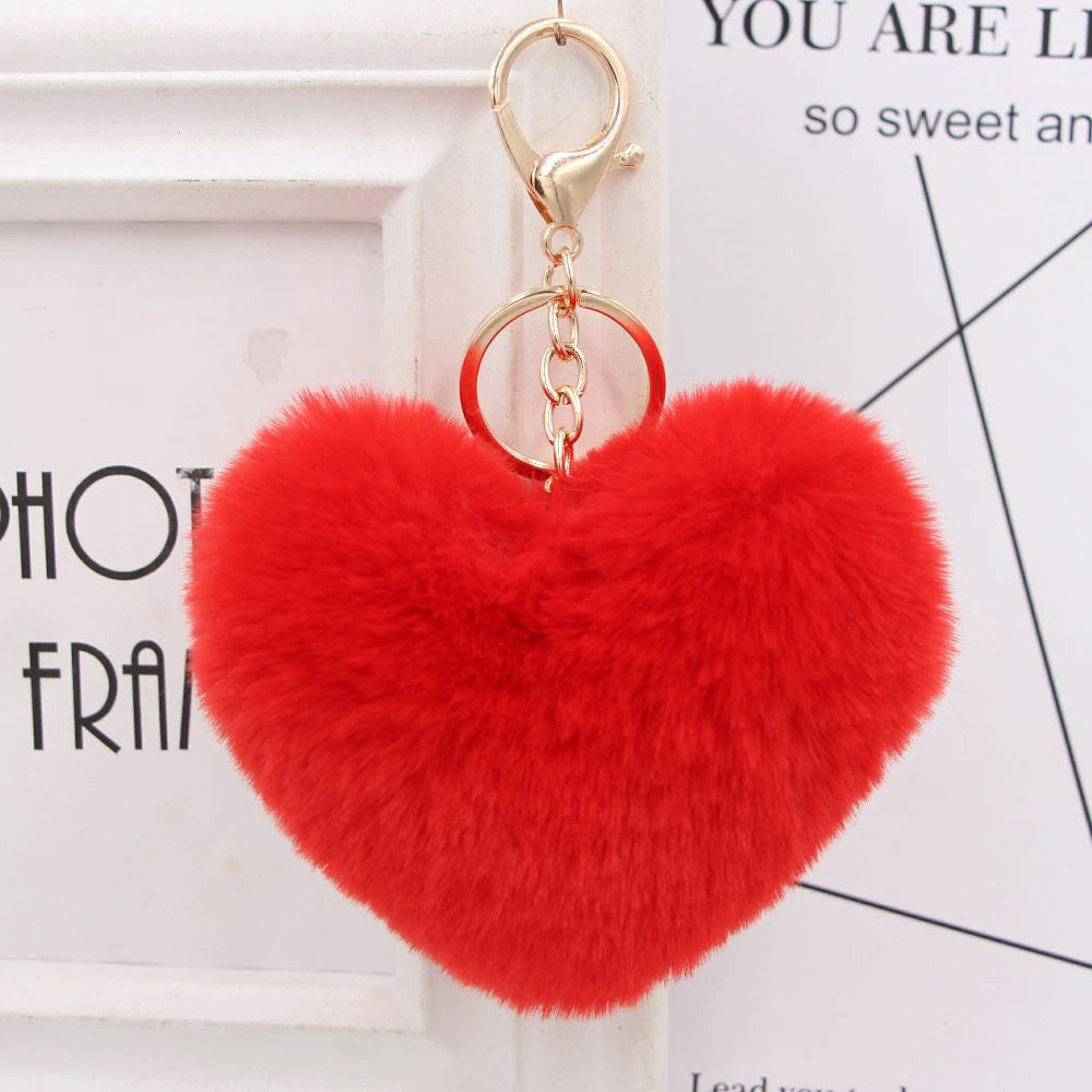 Red heart-shaped fluffy keychain on a white background with text.