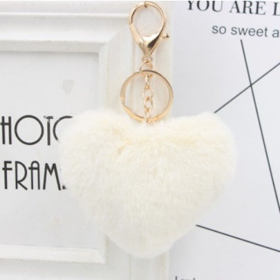 White fluffy keychain with gold ring on a light gray background