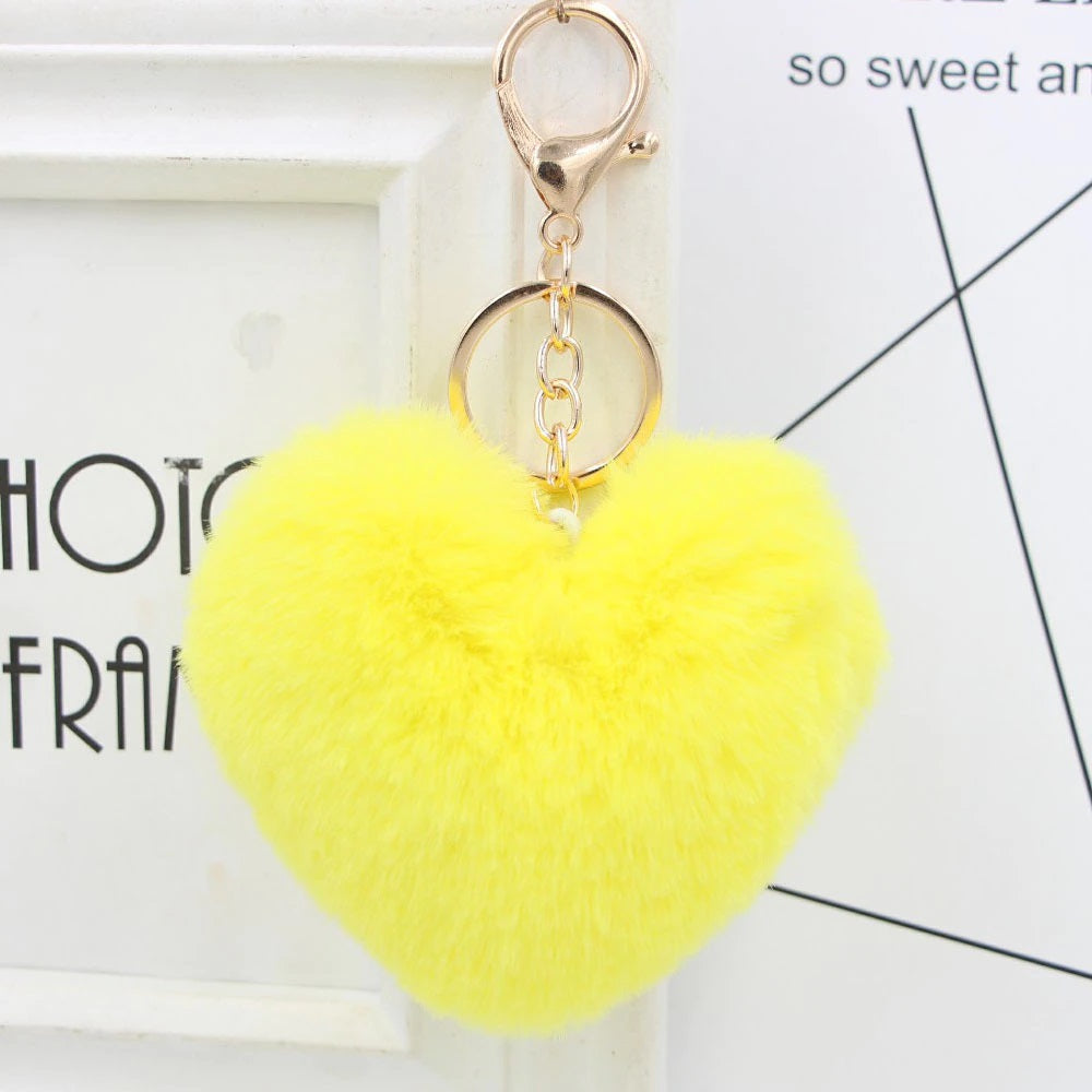 Yellow heart-shaped fluffy keychain on a white background